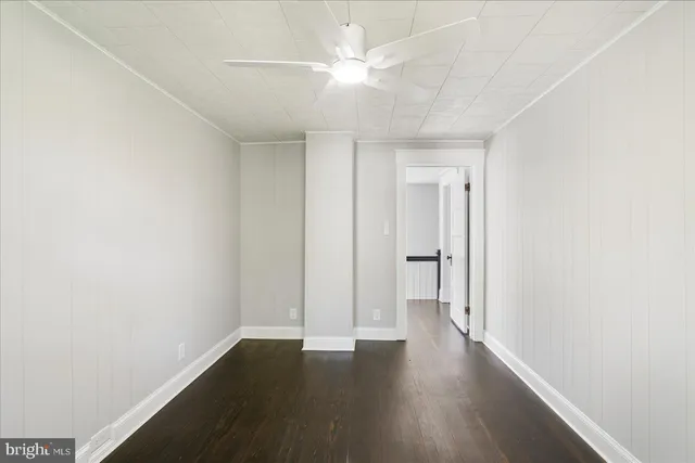 an empty room with wooden floor and ceiling fan