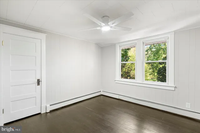 an empty room with wooden floor cabinet and windows