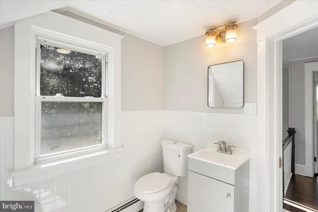 a bathroom with a toilet a sink a mirror and a window