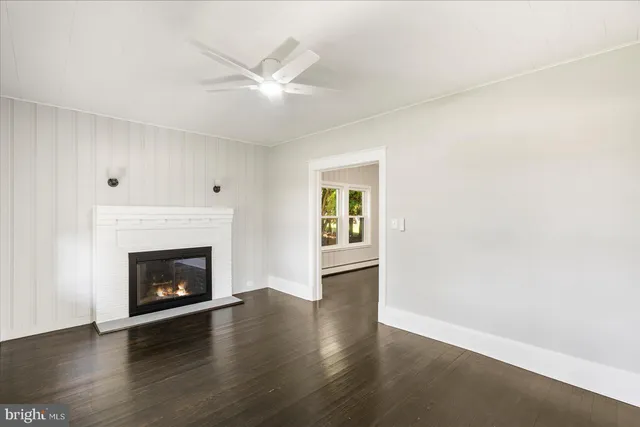 a view of an empty room with wooden floor and a fireplace