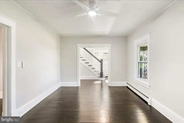 an empty room with wooden floor chandelier fan and windows