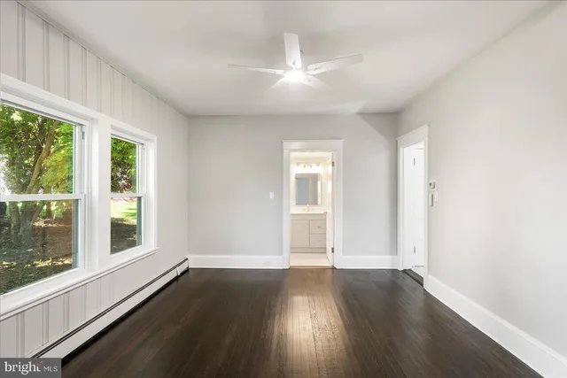 an empty room with wooden floor and windows