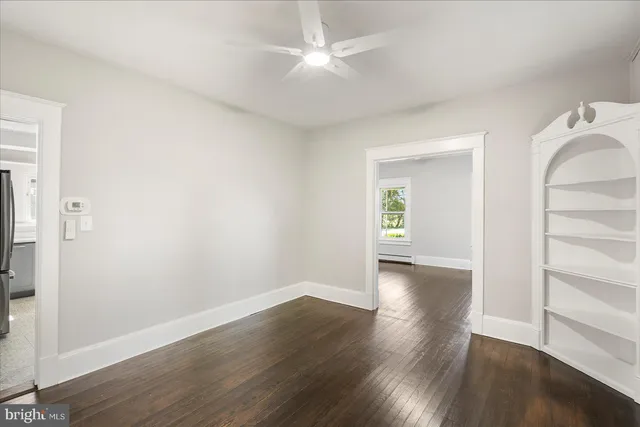 an empty room with wooden floor and a ceiling fan
