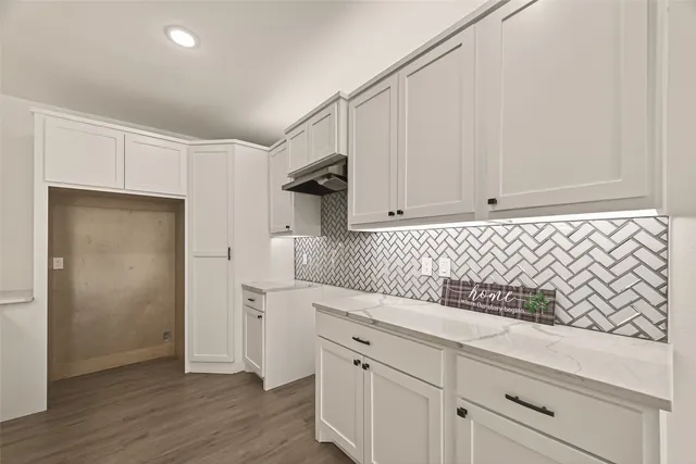 a kitchen with white cabinets and wooden floor