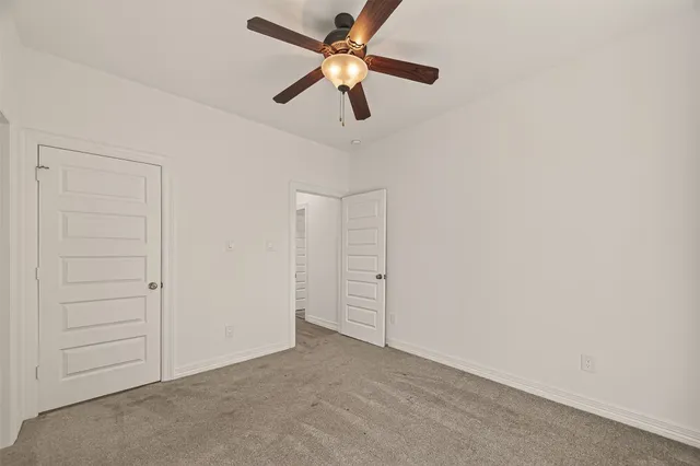 an empty room with closet and ceiling fan
