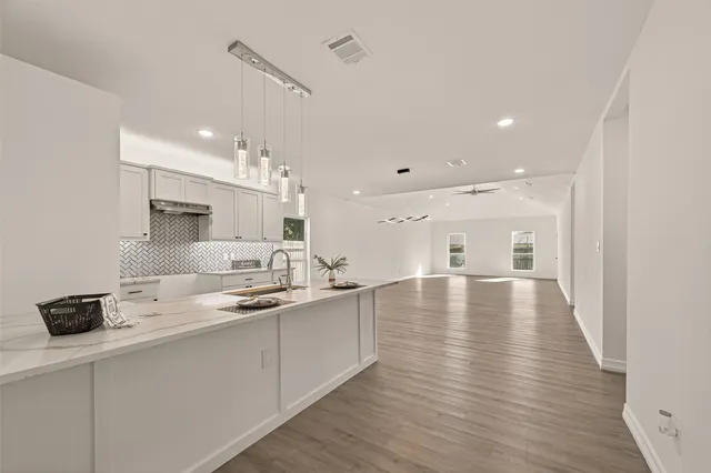 a dining hall with stainless steel appliances granite countertop a sink dishwasher and a stove with wooden floor