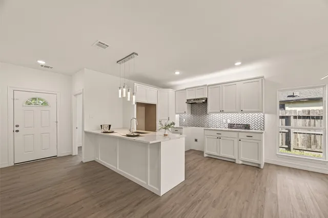 a kitchen with stainless steel appliances granite countertop a stove cabinets and wooden floor