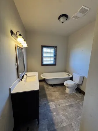 a bathroom with a granite countertop toilet sink and mirror
