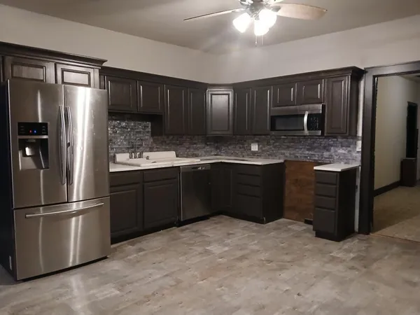 a kitchen with stainless steel appliances granite countertop a refrigerator a stove a sink and a microwave