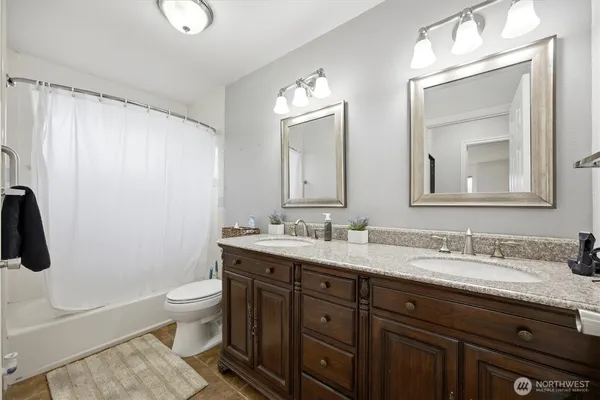 a bathroom with a double vanity sink toilet and mirror