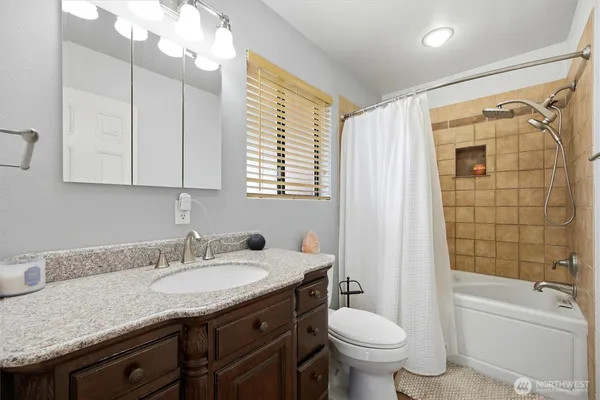 a bathroom with a granite countertop sink toilet and shower