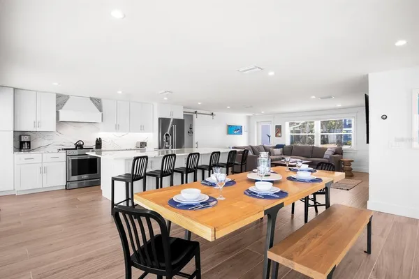 a open dining room with stainless steel appliances kitchen island granite countertop a dining table chairs and kitchen view