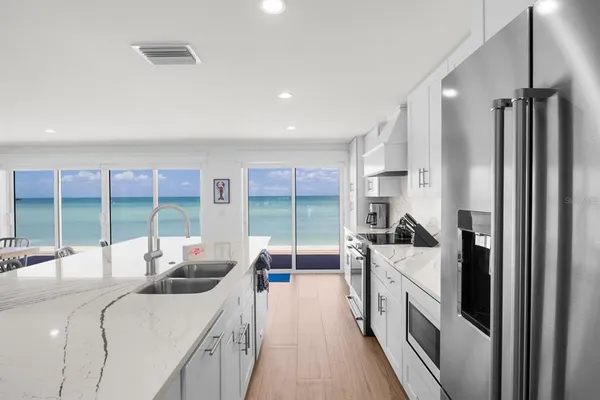 a large white kitchen with a large window and stainless steel appliances