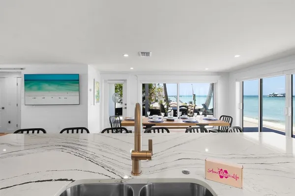 a view of a kitchen with kitchen island a large window cabinets a sink and stainless steel appliances