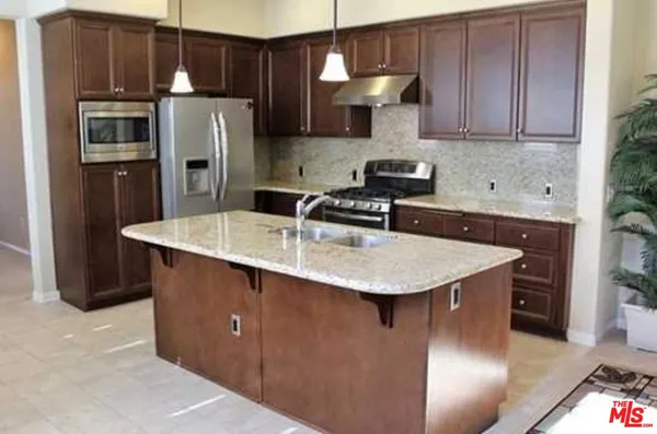 a kitchen with stainless steel appliances granite countertop a sink a refrigerator and a stove