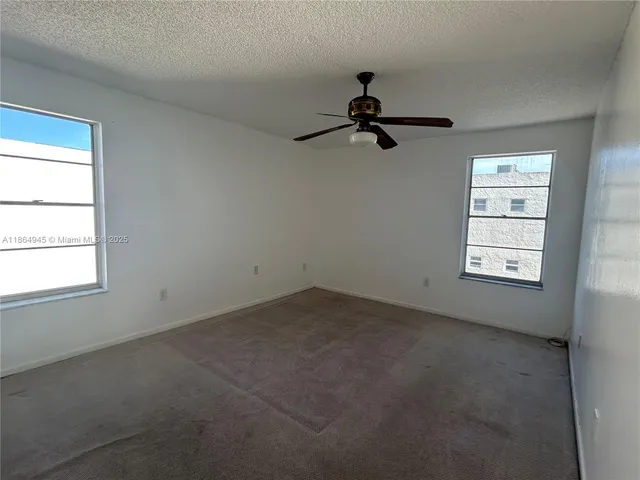 an empty room with windows and ceiling fan view