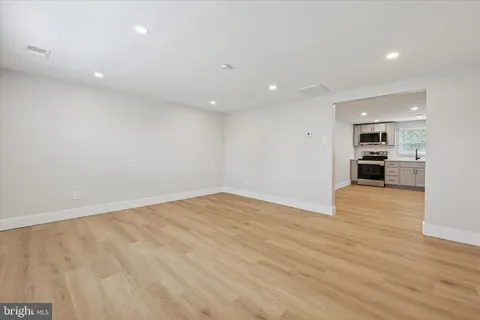 an empty room with wooden floor and a kitchen