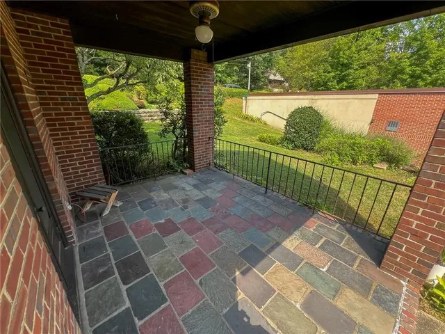 an aerial view of a house with yard and trees in the background