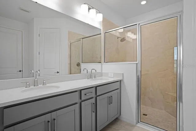 a bathroom with a shower sink vanity and mirror