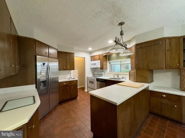 a kitchen with a refrigerator a sink dishwasher with a dining table and chairs