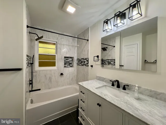 a bathroom with a granite countertop sink a mirror and a bathtub