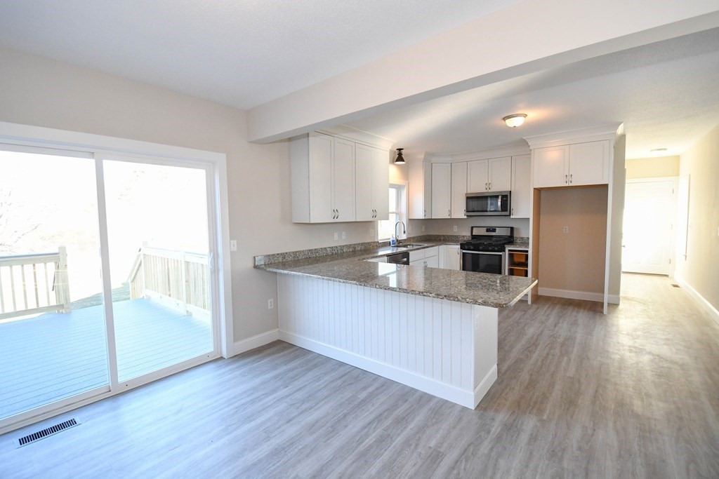 286 Wheeler Road Dracut, MA 01826 - Photo 11 of 32 a kitchen with stainless steel appliances wooden floors and large window