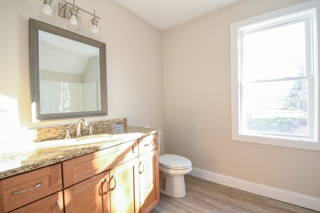 286 Wheeler Road Dracut, MA 01826 - Photo 26 of 32 a bathroom with a granite countertop toilet a sink a mirror and a window