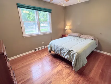 a bedroom with a bed window and wooden floor