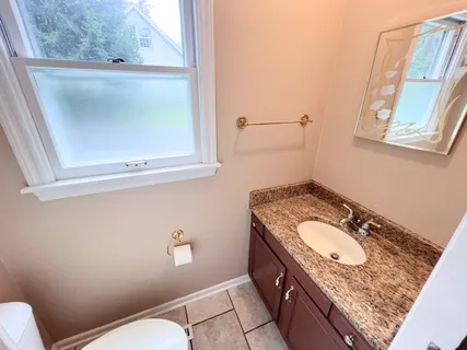 a bathroom with a granite countertop sink a mirror and a toilet