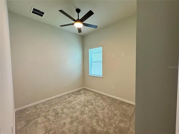 an empty room with a chandelier fan and a window