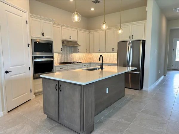 a kitchen with stainless steel appliances granite countertop a refrigerator a sink a stove a microwave and island