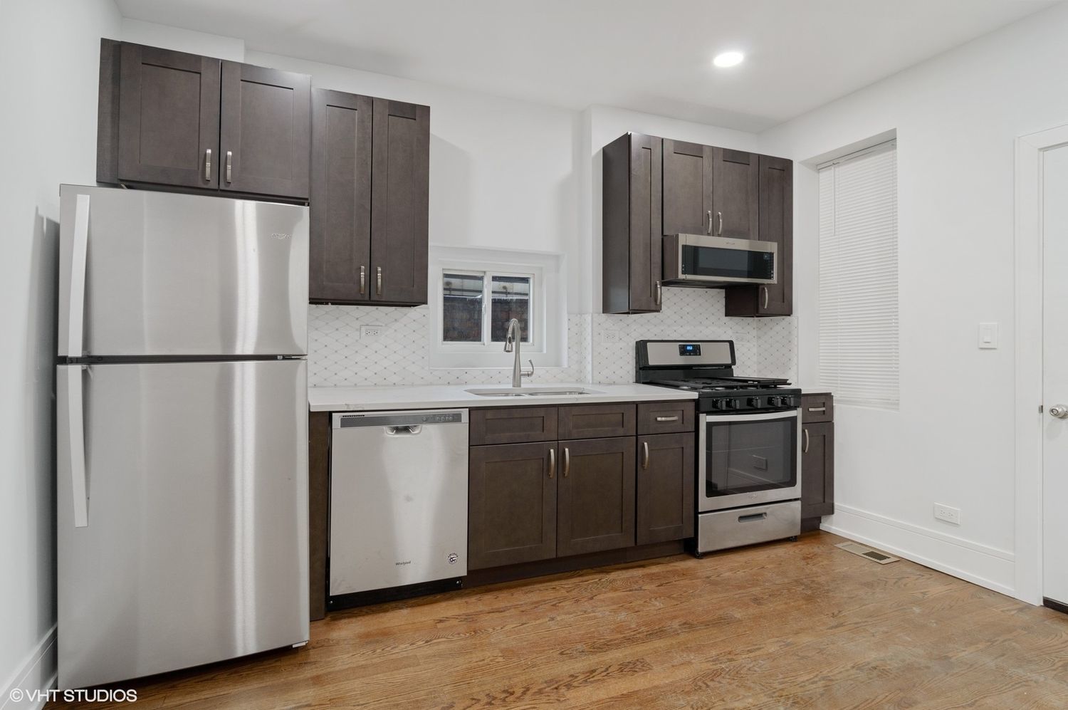 1719 West 18th Street, Unit 2R Chicago, IL 60608 - Photo 3 of 8 a kitchen with stainless steel appliances granite countertop a refrigerator stove a sink and a microwave