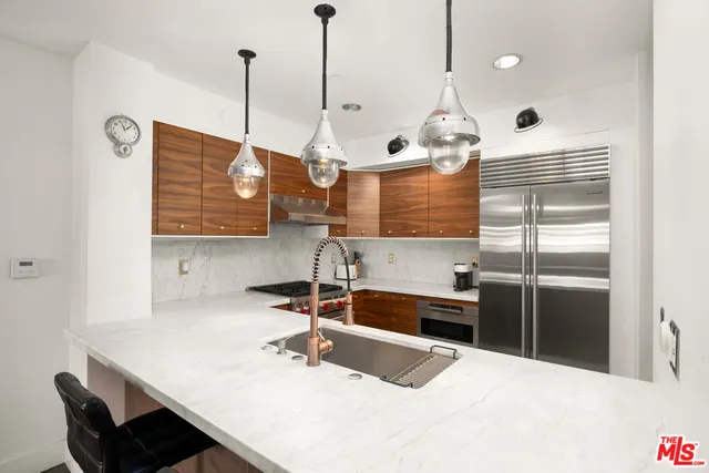 a kitchen with kitchen island a sink stainless steel appliances and a chandelier
