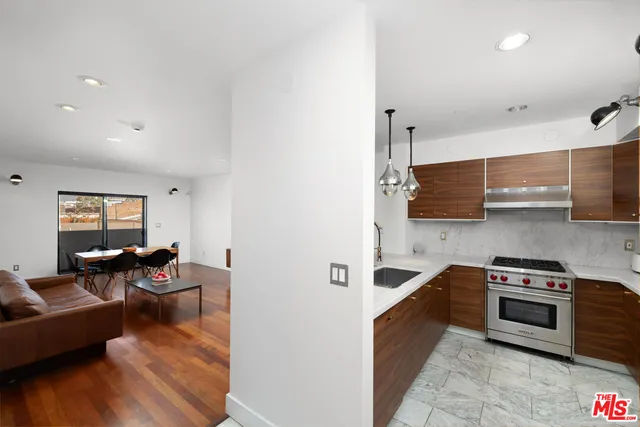 a kitchen with stainless steel appliances a stove a sink a refrigerator wooden floor and cabinets