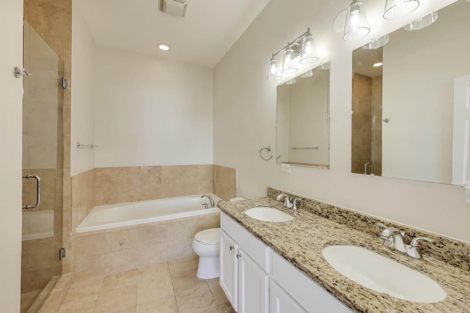 1920 North Springfield Avenue, Unit 1S Chicago, IL 60647 - Photo 15 of 36 a bathroom with a granite countertop sink a toilet a mirror a bathtub and shower