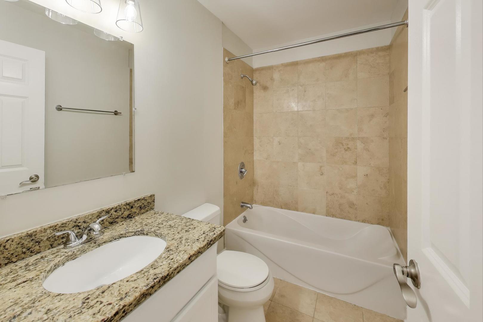 1920 North Springfield Avenue, Unit 1S Chicago, IL 60647 - Photo 19 of 36 a bathroom with a granite countertop sink toilet mirror vanity and bathtub