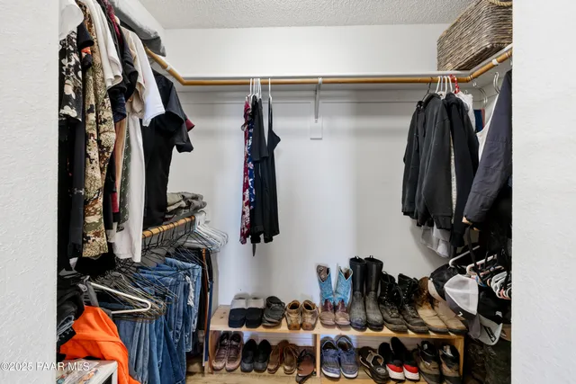 a view of walk in closet with clothes and shoes