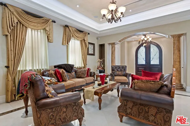 a living room with furniture a chandelier and a large mirror