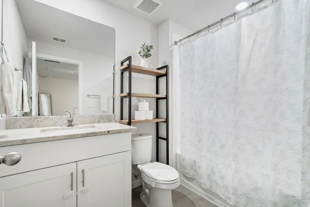 a bathroom with a granite countertop sink toilet and a mirror