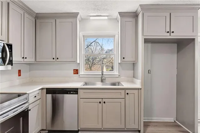 a kitchen with stainless steel appliances granite countertop a sink and dishwasher with white cabinets