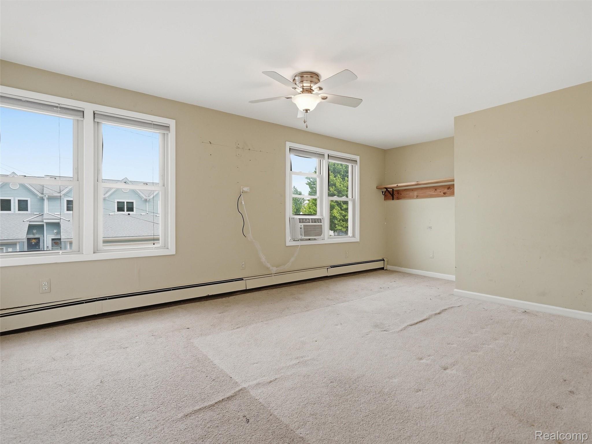 117 Kenyon Road Algonac, MI 48001 - Photo 26 of 47 Expansive room featuring multiple windows, a ceiling fan, baseboard heating, and an open closet space with a built-in shelf