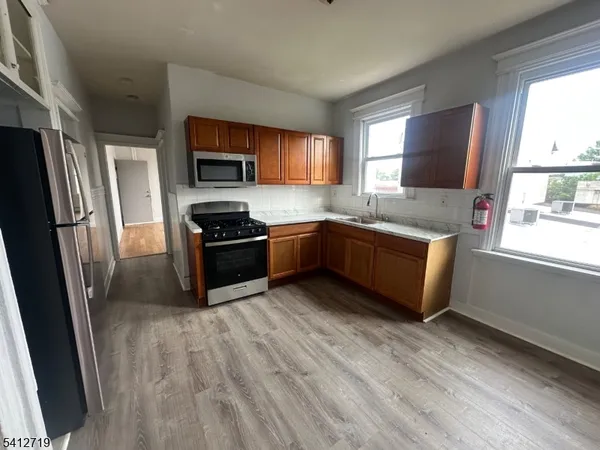 a kitchen with granite countertop a refrigerator and a stove top oven