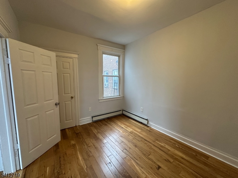 159 21st Street, Unit 2 Irvington, NJ 07111 - Photo 4 of 9 an empty room with wooden floor and windows