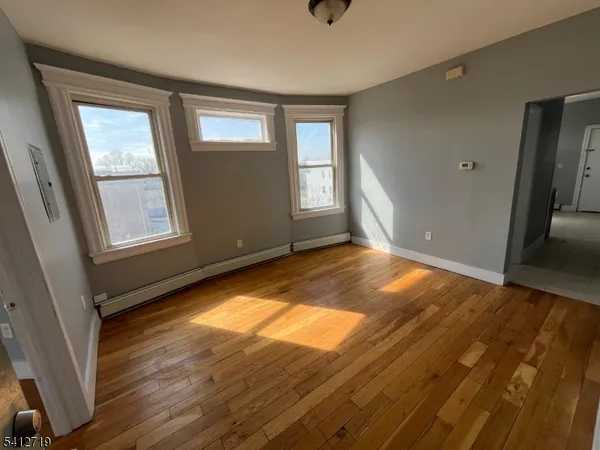 a view of empty room with wooden floor and fan