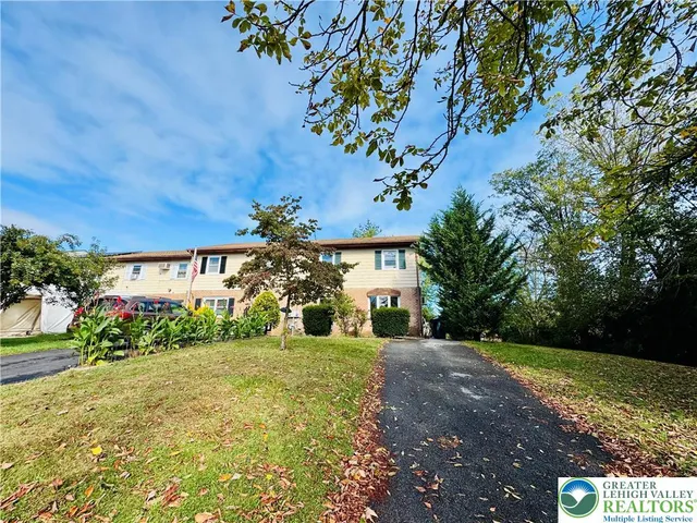 a view of a white house with a big yard and large tree