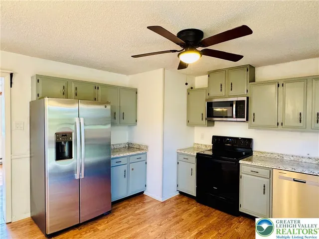a kitchen with stainless steel appliances kitchen island granite countertop a refrigerator a sink a stove with cabinets