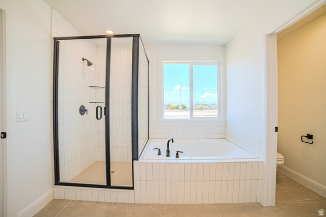 45 North Scarlet Maple Road, Unit 4317 Vineyard, UT 84059 - Photo 18 of 35 Contemporary bathroom featuring a walk-in shower with matte black fixtures, a soaking tub with coordinating matte black faucet, and vertical tile detailing
