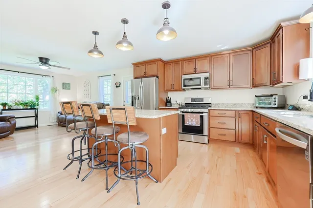 a kitchen with stainless steel appliances granite countertop a stove top oven a sink a dining table and chairs with wooden floor