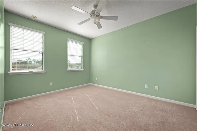 an empty room with windows and fan
