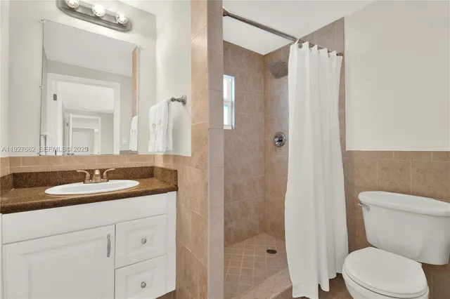 a bathroom with a granite countertop sink toilet a mirror a vanity and shower